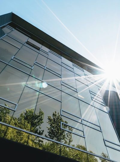 Low angle view of a modern skyscraper with reflections and sun flare, emphasizing contemporary architecture.